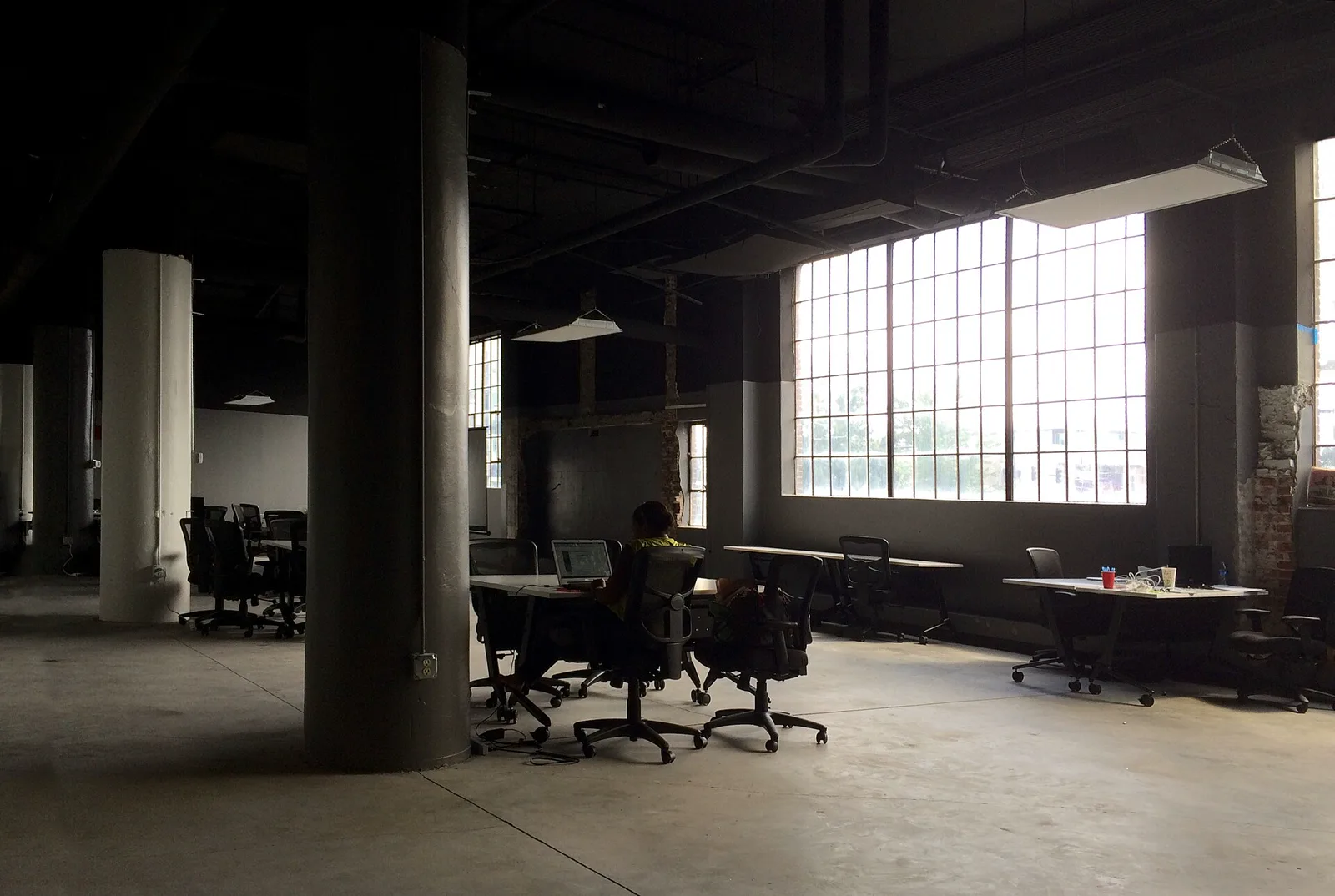 A quiet open-plan office with tall factory windows